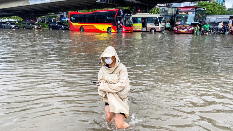 Orang-orang berjalan melalui jalan yang banjir di tengah hujan lebat akibat Topan Matmo, yang menyebabkan kendaraan terlantar, menutup sekolah, memindahkan kelas daring, dan menunda penerbangan ke dan dari Bandara Internasional Noi Bai, di Hanoi, Vietnam, 7 Oktober 2025. (REUTERS/Thinh Tien Nguyen)