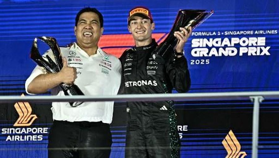 Presiden dan CEO grup Petronas Tengku Muhammad Taufik Tengku Aziz bersama pembalap Mercedes-AMG Petronas George Russell setelah tim meraih kemenangan di Grand Prix F1 Singapura pada 5 Oktober 2025. (Lillian SUWANRUMPHA / AFP)