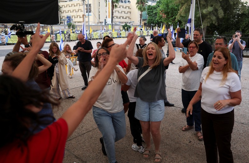 ISRAEL-PALESTINIANS/ Seorang pria mengenakan topeng bergambar Presiden AS Donald Trump memegang bendera Israel dan balon berbentuk hati, sementara orang-orang merayakan setelah Trump mengumumkan bahwa Israel dan Hamas menyepakati fase pertama gencatan senjata Gaza, di