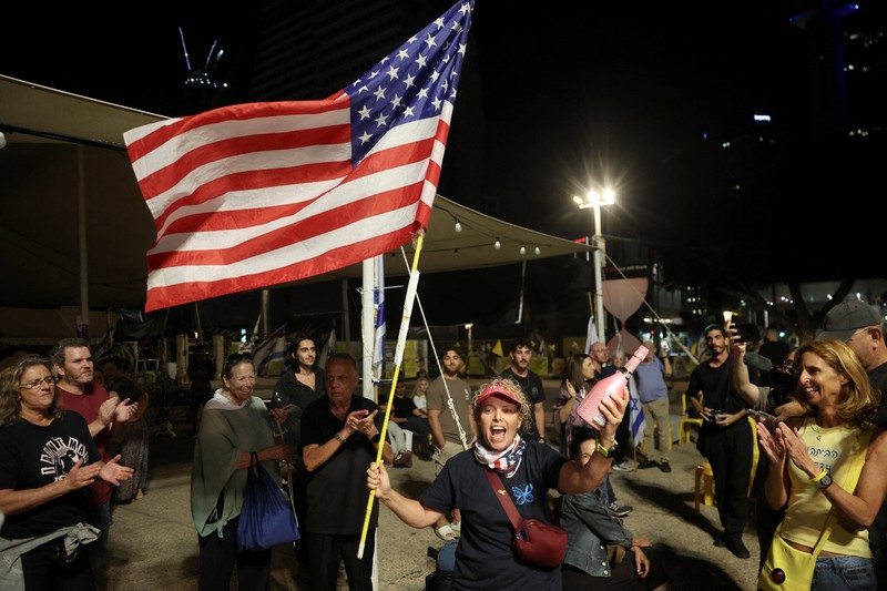 ISRAEL-PALESTINIANS/ Seorang pria mengenakan topeng bergambar Presiden AS Donald Trump memegang bendera Israel dan balon berbentuk hati, sementara orang-orang merayakan setelah Trump mengumumkan bahwa Israel dan Hamas menyepakati fase pertama gencatan senjata Gaza, di