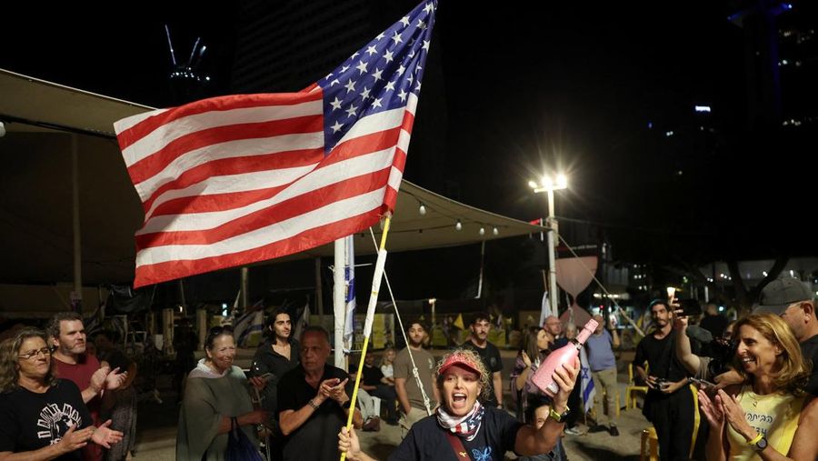 ISRAEL-PALESTINIANS/ Seorang pria mengenakan topeng bergambar Presiden AS Donald Trump memegang bendera Israel dan balon berbentuk hati, sementara orang-orang merayakan setelah Trump mengumumkan bahwa Israel dan Hamas menyepakati fase pertama gencatan senjata Gaza, di