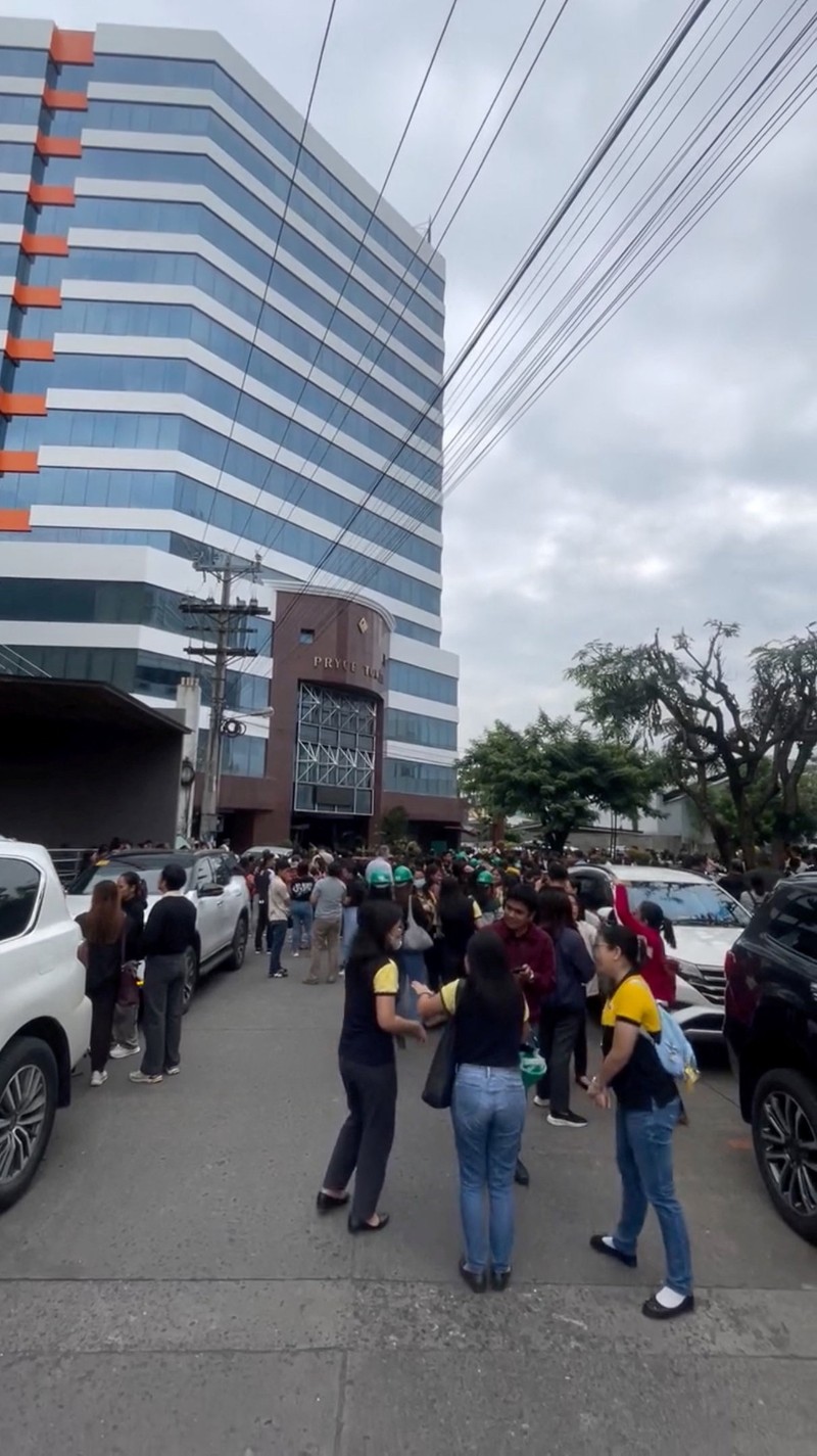 Para karyawan sebuah pusat perbelanjaan berkumpul di luar gedung di Kota Davao, di pulau selatan Mindanao, pada 10 Oktober 2025, setelah gempa berkekuatan 7,4 skala Richter melanda Filipina selatan.(Photo by Bobbie ALOTA / AFP)