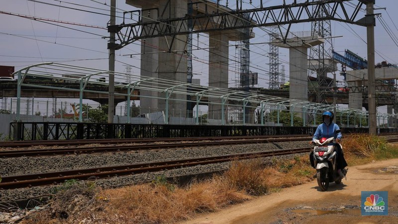Warga berjalan melintas di dekat proyek Stasiun Jakarta International Stadium (JIS) di kawasan Tanjung Priok, Jakarta, Jumat (10/10/2025). (CNBC Indonesia/Faisal Rahman)