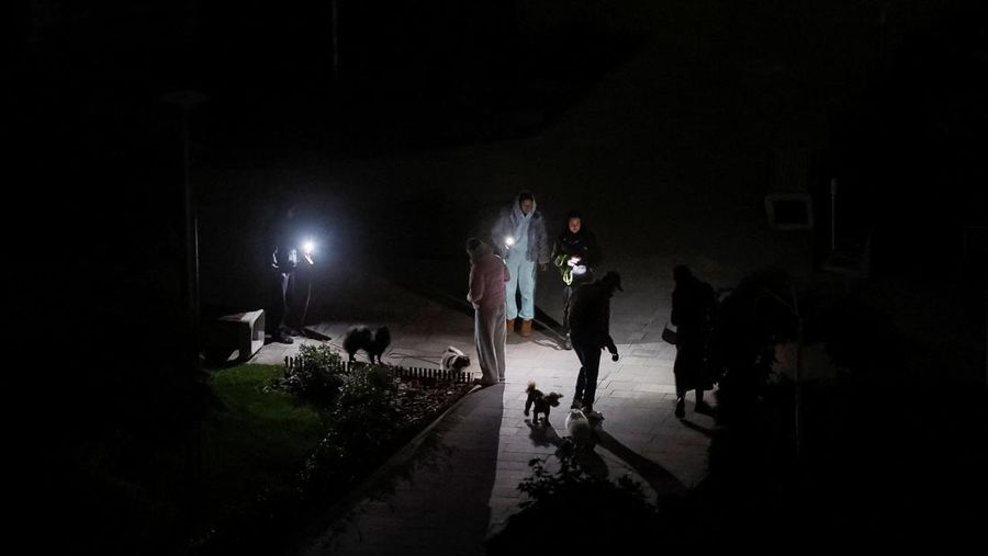 Seorang wanita menyeberang jalan dengan anjingnya saat listrik padam setelah infrastruktur sipil penting terkena serangan rudal dan pesawat tak berawak Rusia baru-baru ini, di tengah serangan Rusia terhadap Ukraina, di Kyiv, Ukraina, 14 Oktober 2025. Seorang wanita menyeberang jalan dengan anjingnya saat listrik padam setelah infrastruktur sipil penting terkena serangan rudal dan pesawat tak berawak Rusia baru-baru ini, di tengah serangan Rusia terhadap Ukraina, di Kyiv, Ukraina, 14 Oktober 2025. (REUTERS/Gleb Garanich)