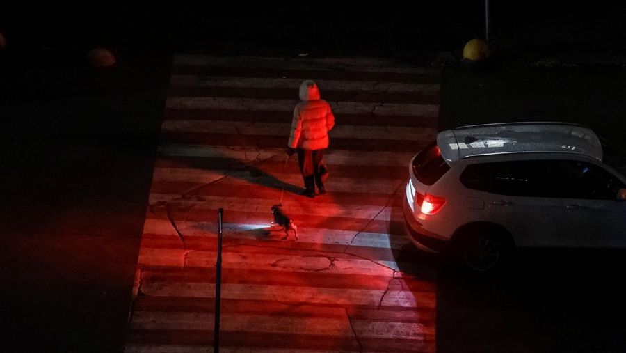 Seorang wanita menyeberang jalan dengan anjingnya saat listrik padam setelah infrastruktur sipil penting terkena serangan rudal dan pesawat tak berawak Rusia baru-baru ini, di tengah serangan Rusia terhadap Ukraina, di Kyiv, Ukraina, 14 Oktober 2025. Seorang wanita menyeberang jalan dengan anjingnya saat listrik padam setelah infrastruktur sipil penting terkena serangan rudal dan pesawat tak berawak Rusia baru-baru ini, di tengah serangan Rusia terhadap Ukraina, di Kyiv, Ukraina, 14 Oktober 2025. (REUTERS/Gleb Garanich)