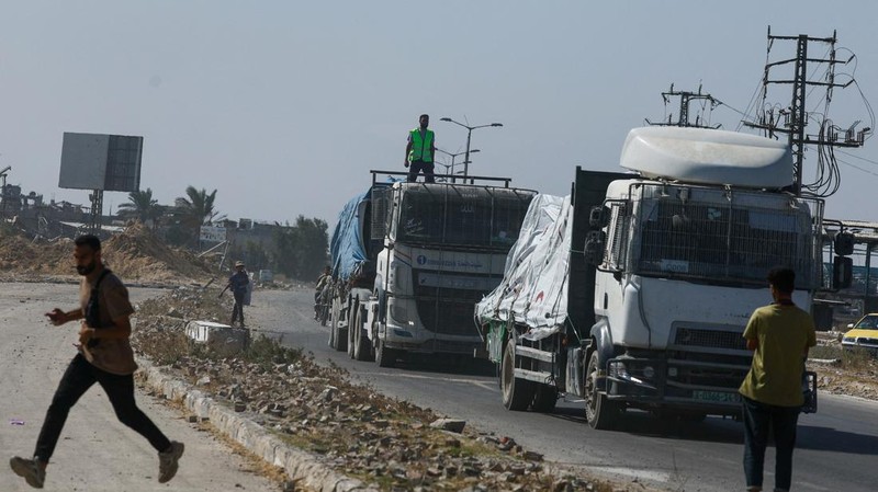 Para relawan Mesir beristirahat dan duduk di samping truk-truk yang membawa bantuan kemanusiaan dari Aliansi Nasional Mesir untuk Pekerjaan Pembangunan Sipil (NACDW) saat mereka menuju perbatasan Rafah untuk memasuki Gaza, setelah gencatan senjata antara Israel dan Hamas di Gaza berlaku, di jalan gurun Kairo-Ismailia, Mesir, 16 Oktober 2025. (REUTERS/Amr Abdallah Dalsh)