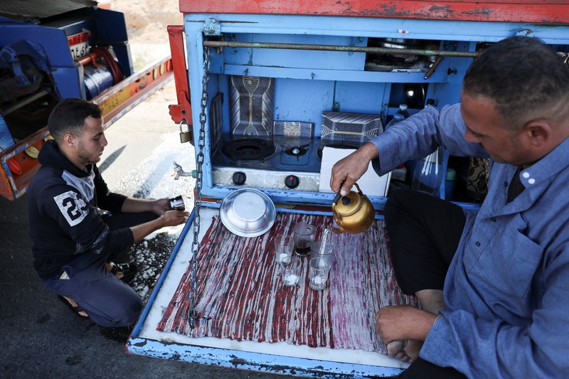 Para relawan Mesir beristirahat dan duduk di samping truk-truk yang membawa bantuan kemanusiaan dari Aliansi Nasional Mesir untuk Pekerjaan Pembangunan Sipil (NACDW) saat mereka menuju perbatasan Rafah untuk memasuki Gaza, setelah gencatan senjata antara Israel dan Hamas di Gaza berlaku, di jalan gurun Kairo-Ismailia, Mesir, 16 Oktober 2025. (REUTERS/Amr Abdallah Dalsh)