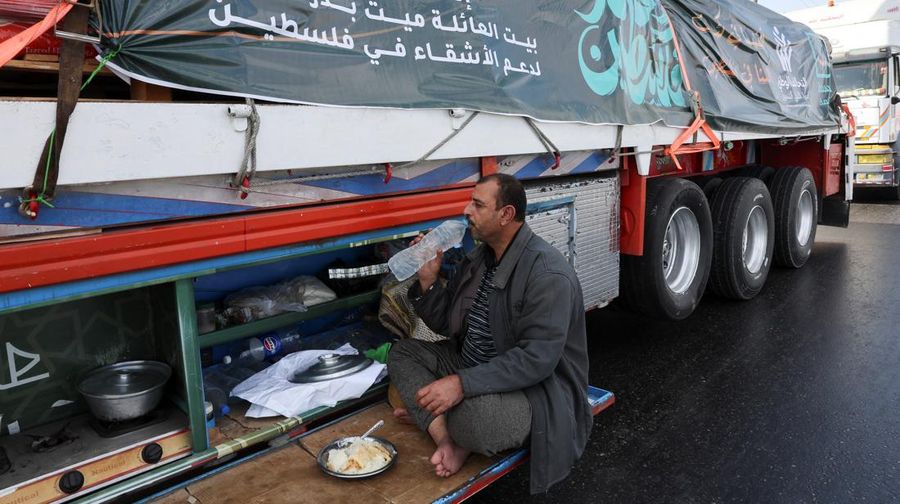 Para relawan Mesir beristirahat dan duduk di samping truk-truk yang membawa bantuan kemanusiaan dari Aliansi Nasional Mesir untuk Pekerjaan Pembangunan Sipil (NACDW) saat mereka menuju perbatasan Rafah untuk memasuki Gaza, setelah gencatan senjata antara Israel dan Hamas di Gaza berlaku, di jalan gurun Kairo-Ismailia, Mesir, 16 Oktober 2025. (REUTERS/Amr Abdallah Dalsh)