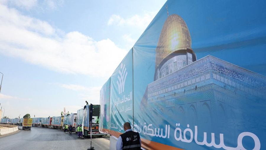 Para relawan Mesir beristirahat dan duduk di samping truk-truk yang membawa bantuan kemanusiaan dari Aliansi Nasional Mesir untuk Pekerjaan Pembangunan Sipil (NACDW) saat mereka menuju perbatasan Rafah untuk memasuki Gaza, setelah gencatan senjata antara Israel dan Hamas di Gaza berlaku, di jalan gurun Kairo-Ismailia, Mesir, 16 Oktober 2025. (REUTERS/Amr Abdallah Dalsh)