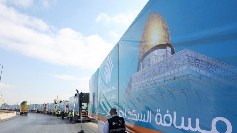 Para relawan Mesir beristirahat dan duduk di samping truk-truk yang membawa bantuan kemanusiaan dari Aliansi Nasional Mesir untuk Pekerjaan Pembangunan Sipil (NACDW) saat mereka menuju perbatasan Rafah untuk memasuki Gaza, setelah gencatan senjata antara Israel dan Hamas di Gaza berlaku, di jalan gurun Kairo-Ismailia, Mesir, 16 Oktober 2025. (REUTERS/Amr Abdallah Dalsh)