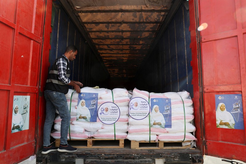 Para relawan Mesir beristirahat dan duduk di samping truk-truk yang membawa bantuan kemanusiaan dari Aliansi Nasional Mesir untuk Pekerjaan Pembangunan Sipil (NACDW) saat mereka menuju perbatasan Rafah untuk memasuki Gaza, setelah gencatan senjata antara Israel dan Hamas di Gaza berlaku, di jalan gurun Kairo-Ismailia, Mesir, 16 Oktober 2025. (REUTERS/Amr Abdallah Dalsh)