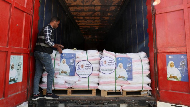 Para relawan Mesir beristirahat dan duduk di samping truk-truk yang membawa bantuan kemanusiaan dari Aliansi Nasional Mesir untuk Pekerjaan Pembangunan Sipil (NACDW) saat mereka menuju perbatasan Rafah untuk memasuki Gaza, setelah gencatan senjata antara Israel dan Hamas di Gaza berlaku, di jalan gurun Kairo-Ismailia, Mesir, 16 Oktober 2025. (REUTERS/Amr Abdallah Dalsh)