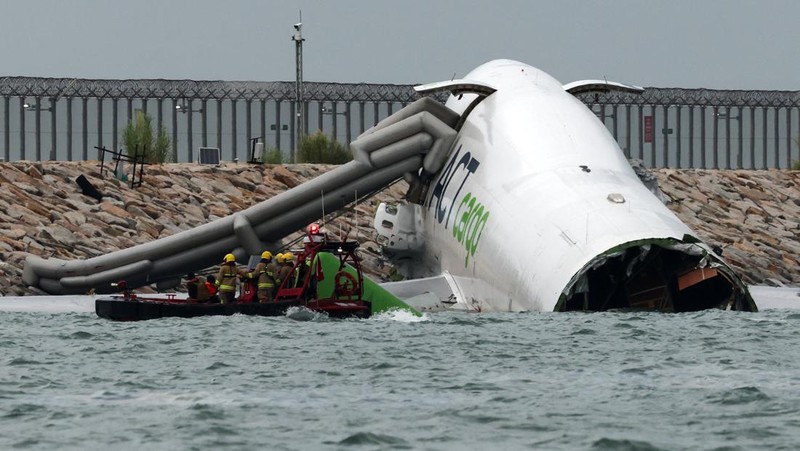 Sebuah pesawat kargo sebagian berada di laut setelah keluar dari landasan pacu saat mendarat di Bandara Internasional Hong Kong di Hong Kong, Cina, 20 Oktober 2025. (REUTERS/Tyrone Siu)