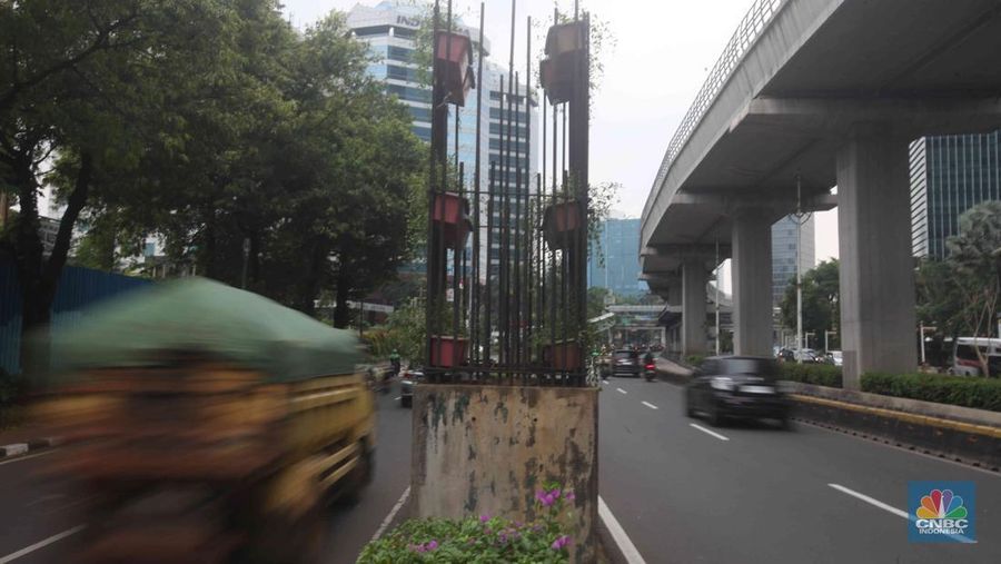 Pengendara melintas di samping tiang monorel yang mangkrak di kawasan Kuningan, Jakarta, Selasa (21/10/2025). (CNBC Indonesia/Muhammad Sabki)