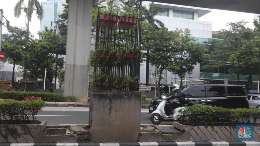 Pengendara melintas di samping tiang monorel yang mangkrak di kawasan Kuningan, Jakarta, Selasa (21/10/2025). (CNBC Indonesia/Muhammad Sabki)