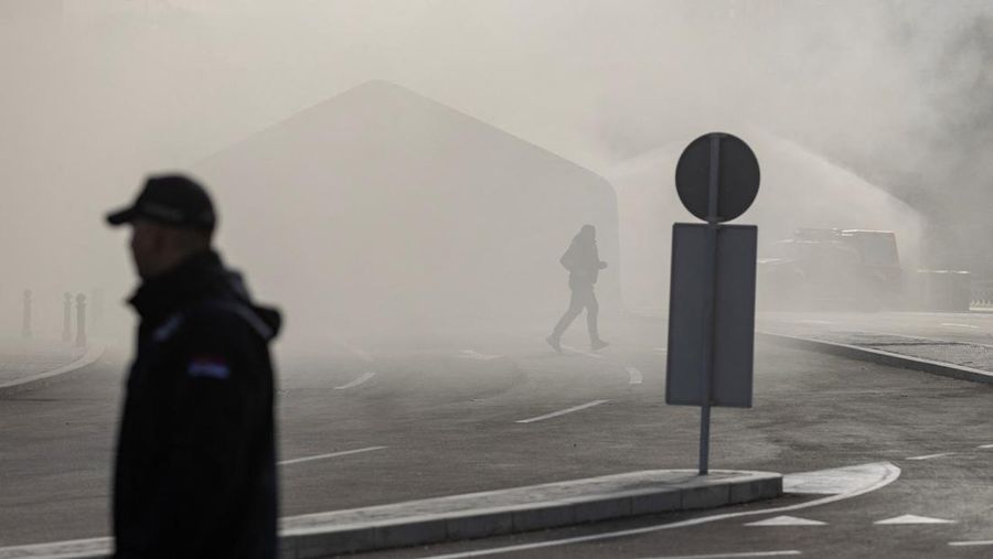 Petugas polisi mengamankan area saat asap mengepul dari tenda yang terbakar menyusul insiden di depan Parlemen di Beograd, Serbia, 22 Oktober 2025. (REUTERS/Djordje Kojadinovic)