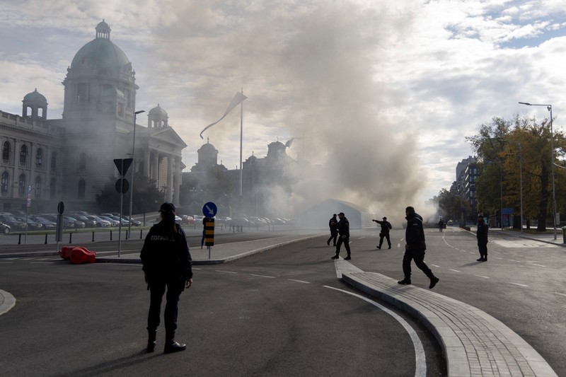 Petugas polisi mengamankan area saat asap mengepul dari tenda yang terbakar menyusul insiden di depan Parlemen di Beograd, Serbia, 22 Oktober 2025. Petugas polisi mengamankan area saat asap mengepul dari tenda yang terbakar menyusul insiden di depan Parlemen di Beograd, Serbia, 22 Oktober 2025. (REUTERS/Djordje Kojadinovic)