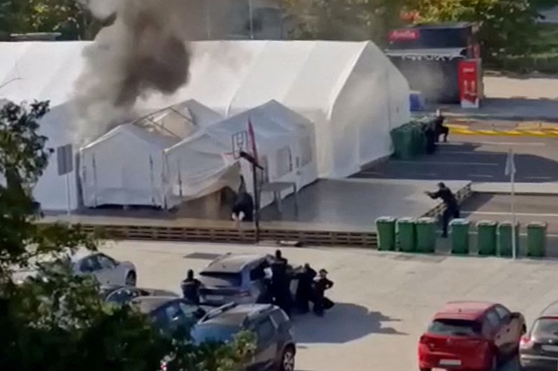 Petugas polisi mengamankan area saat asap mengepul dari tenda yang terbakar menyusul insiden di depan Parlemen di Beograd, Serbia, 22 Oktober 2025. Petugas polisi mengamankan area saat asap mengepul dari tenda yang terbakar menyusul insiden di depan Parlemen di Beograd, Serbia, 22 Oktober 2025. (REUTERS/Djordje Kojadinovic)