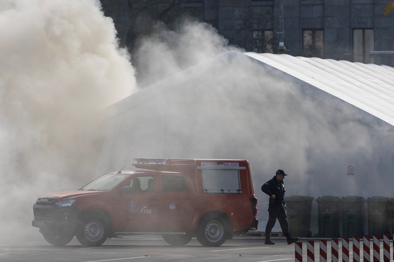Petugas polisi mengamankan area saat asap mengepul dari tenda yang terbakar menyusul insiden di depan Parlemen di Beograd, Serbia, 22 Oktober 2025. Petugas polisi mengamankan area saat asap mengepul dari tenda yang terbakar menyusul insiden di depan Parlemen di Beograd, Serbia, 22 Oktober 2025. (REUTERS/Djordje Kojadinovic)