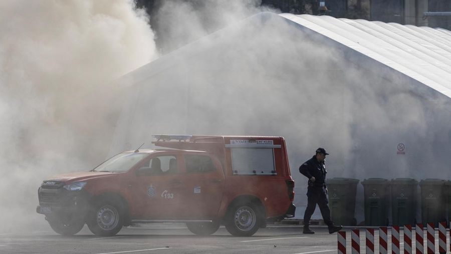 Petugas polisi mengamankan area saat asap mengepul dari tenda yang terbakar menyusul insiden di depan Parlemen di Beograd, Serbia, 22 Oktober 2025. (REUTERS/Djordje Kojadinovic)