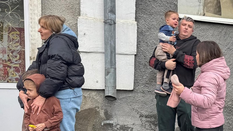 Seorang warga melihat mobil yang rusak saat petugas pemadam kebakaran bekerja di lokasi taman kanak-kanak yang terkena serangan pesawat tak berawak Rusia, di tengah serangan Rusia terhadap Ukraina, di Kharkiv, Ukraina, 22 Oktober 2025. (REUTERS/Sofiia Gatilova)
