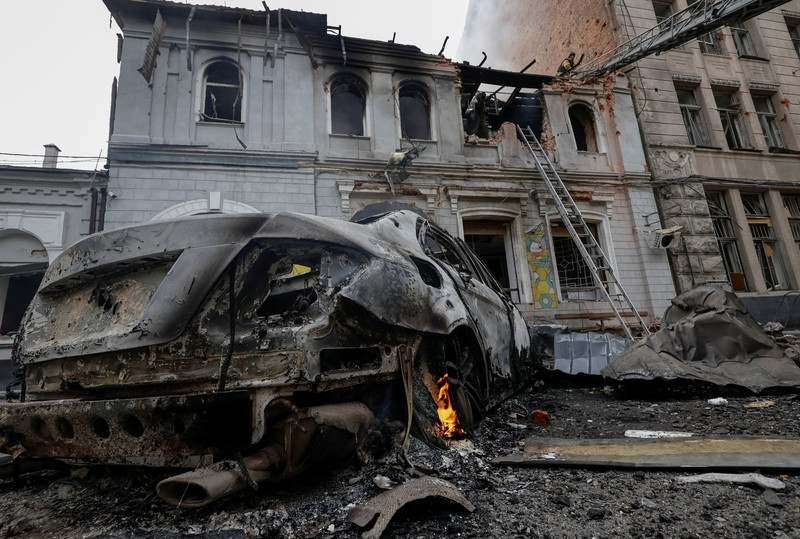 Seorang warga melihat mobil yang rusak saat petugas pemadam kebakaran bekerja di lokasi taman kanak-kanak yang terkena serangan pesawat tak berawak Rusia, di tengah serangan Rusia terhadap Ukraina, di Kharkiv, Ukraina, 22 Oktober 2025. Seorang warga melihat mobil yang rusak saat petugas pemadam kebakaran bekerja di lokasi taman kanak-kanak yang terkena serangan pesawat tak berawak Rusia, di tengah serangan Rusia terhadap Ukraina, di Kharkiv, Ukraina, 22 Oktober 2025. (REUTERS/Sofiia Gatilova)
