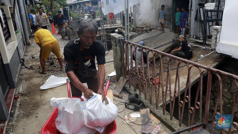 Sejumlah warga melakukan pengangkutan puing material jembatan warga di Gang Saluran yang ambruk, Matraman, Jakarta Timur, Kamis (23/10/2025). (CNBC Indonesia/Muhammad Sabki)