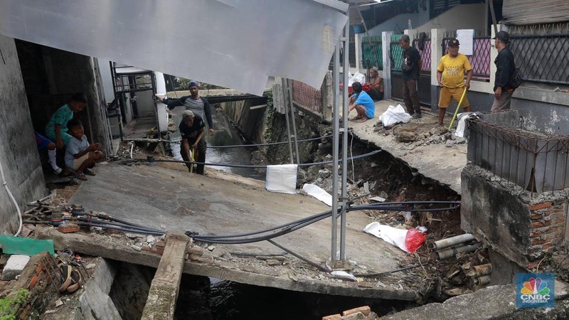 Sejumlah warga melakukan pengangkutan puing material jembatan warga di Gang Saluran yang ambruk, Matraman, Jakarta Timur, Kamis (23/10/2025). (CNBC Indonesia/Muhammad Sabki)