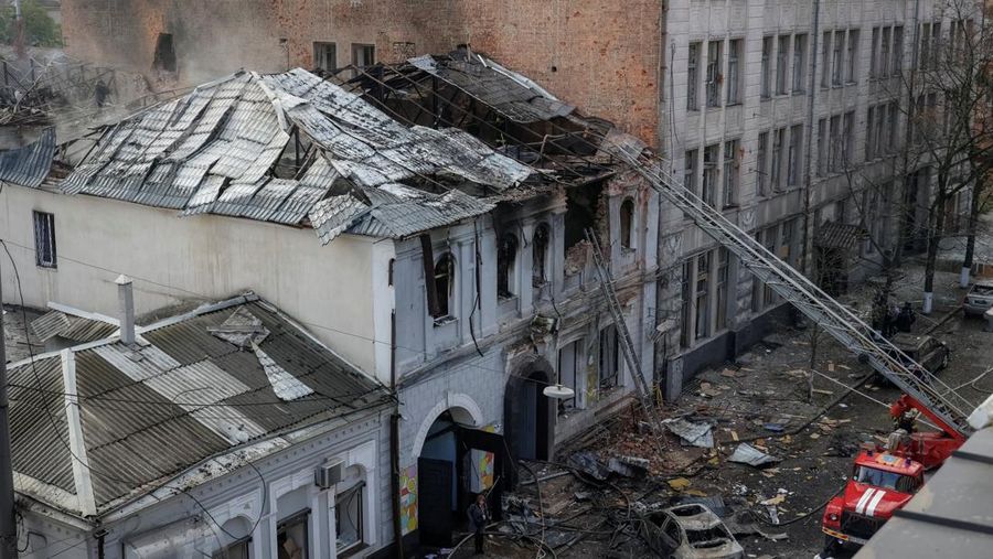 Seorang warga melihat mobil yang rusak saat petugas pemadam kebakaran bekerja di lokasi taman kanak-kanak yang terkena serangan pesawat tak berawak Rusia, di tengah serangan Rusia terhadap Ukraina, di Kharkiv, Ukraina, 22 Oktober 2025. (REUTERS/Sofiia Gatilova)
