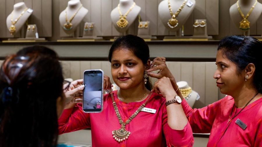 Asisten penjualan menunjukkan perhiasan emas kepada pelanggan menggunakan ponsel, di ruang pamer perhiasan di Ahmedabad, India, 18 Oktober 2025. REUTERS/Amit Dave