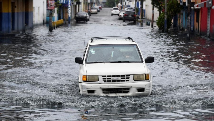 Seorang wanita berdiri di jalan yang tergenang air akibat hujan yang disebabkan oleh Badai Tropis Melissa, di Santo Domingo, Republik Dominika, 23 Oktober 2025. (REUTERS/Eddy Vittini)