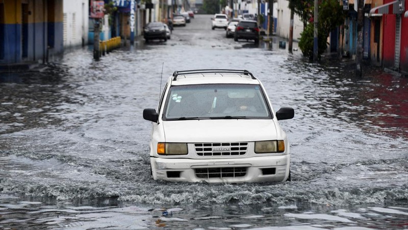 Seorang wanita berdiri di jalan yang tergenang air akibat hujan yang disebabkan oleh Badai Tropis Melissa, di Santo Domingo, Republik Dominika, 23 Oktober 2025. (REUTERS/Eddy Vittini)