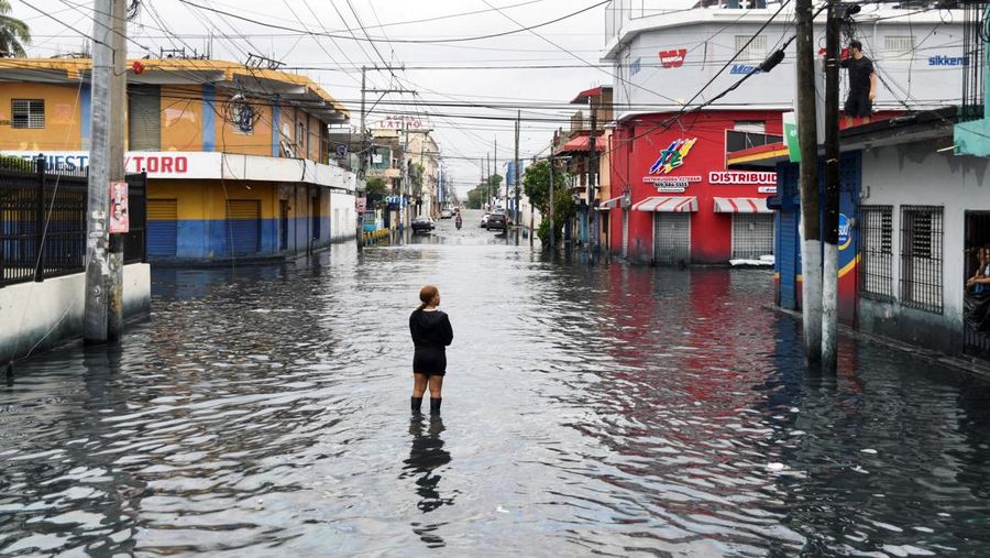 Seorang wanita berdiri di jalan yang tergenang air akibat hujan yang disebabkan oleh Badai Tropis Melissa, di Santo Domingo, Republik Dominika, 23 Oktober 2025. (REUTERS/Eddy Vittini)