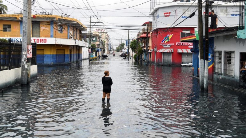Seorang wanita berdiri di jalan yang tergenang air akibat hujan yang disebabkan oleh Badai Tropis Melissa, di Santo Domingo, Republik Dominika, 23 Oktober 2025. (REUTERS/Eddy Vittini)
