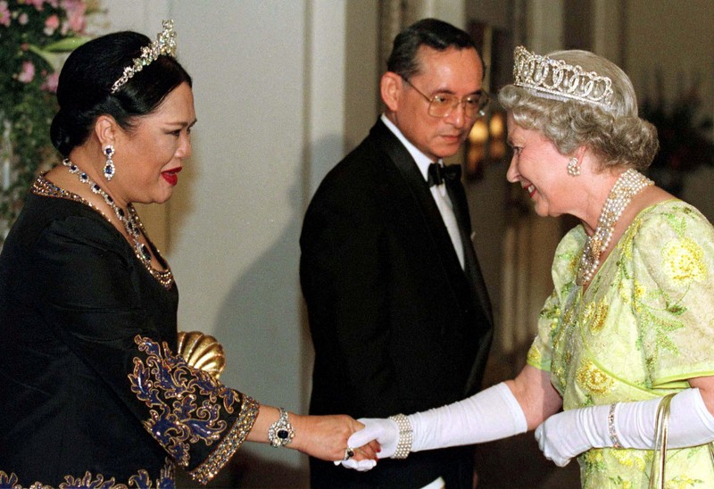 THAILAND-QUEENMOTHER/ FILE PHOTO: Britain's Queen Elizabeth II smiles as she greets Thailand's Queen Sirikit as the King Bhumibol Adulyadej looks on at a reception at the British Ambassador's residence in central Bangkok, Thailand October 30, 1996. REUTERS/Dylan Martinez/File Photo