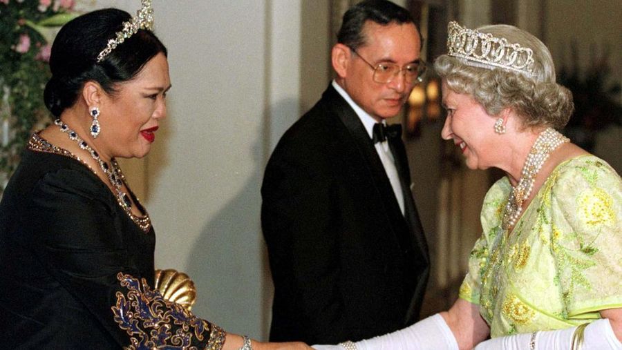 THAILAND-QUEENMOTHER/  Britain's Queen Elizabeth II smiles as she greets Thailand's Queen Sirikit as the King Bhumibol Adulyadej looks on at a reception at the British Ambassador's residence in central Bangkok, Thailand October 30, 1996. REUTERS/Dylan Martinez/File Photo