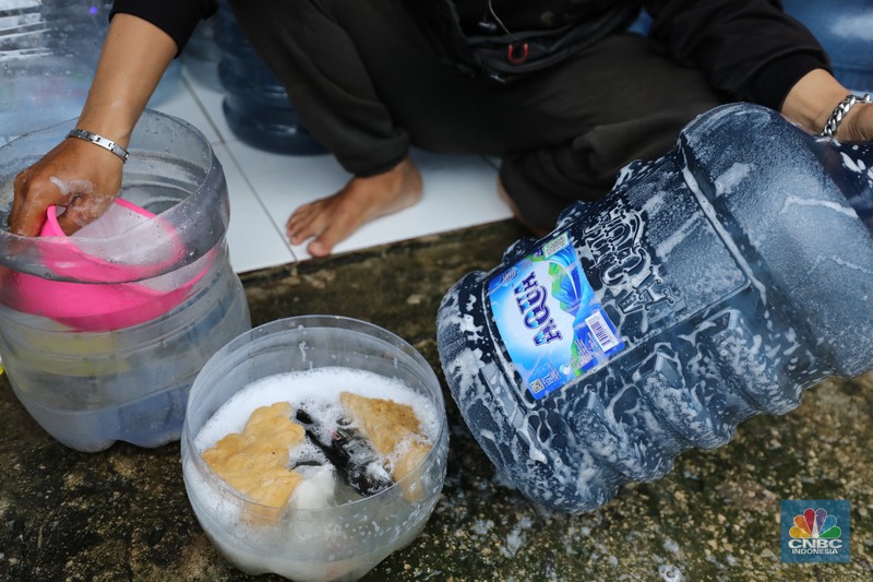 Pekerja mengisi air isi ulang galon di kawasan Depok, Jawa Barat, Selasa (28/10/2025). (CNBC Indonesia/Tri Susilo)