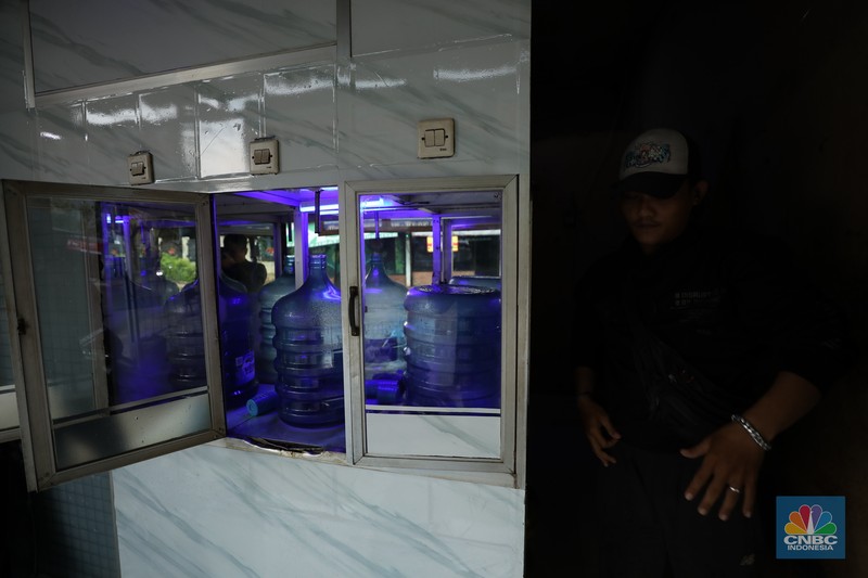 Pekerja mengisi air isi ulang galon di kawasan Depok, Jawa Barat, Selasa (28/10/2025). (CNBC Indonesia/Tri Susilo)