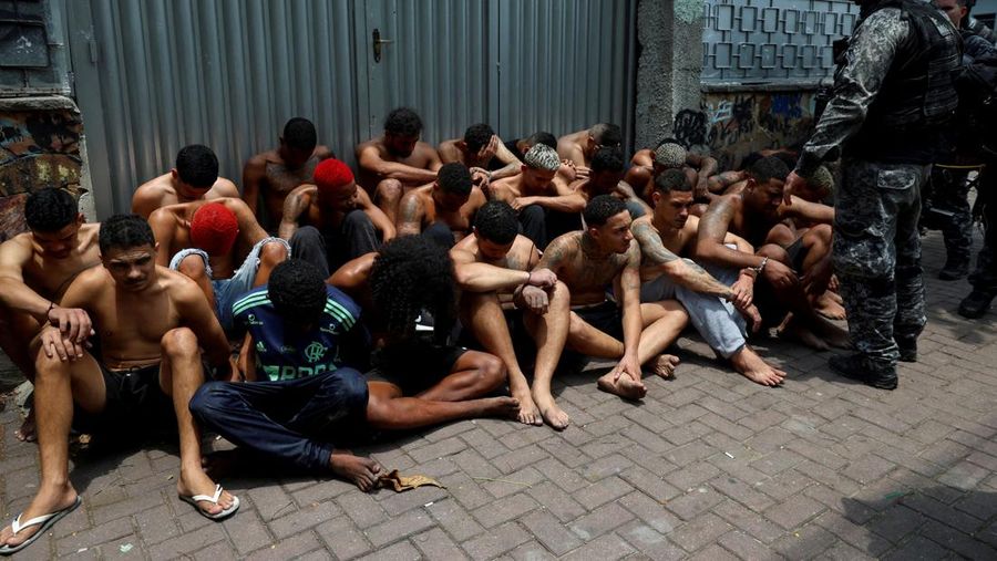 Suspected drug dealers sit on the ground after they were detained by members of the military police special unit, during a police operation against drug trafficking at the favela do Penha, in Rio de Janeiro, Brazil October 28, 2025. REUTERS/Aline Massuca        TPX IMAGES OF THE DAY