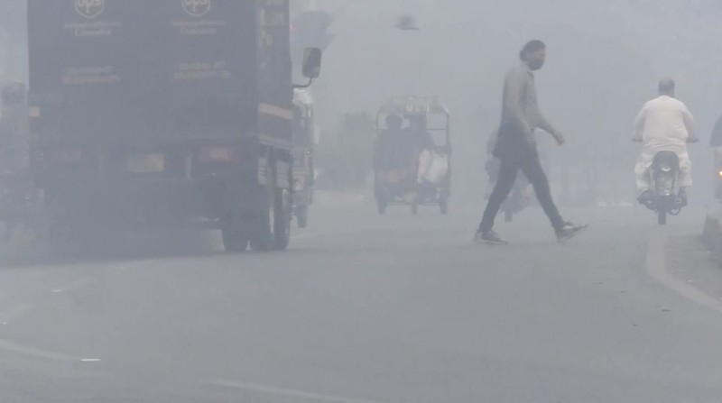 Para siswa terlihat siluetnya saat menyeberangi jembatan penyeberangan di tengah kabut asap dan polusi udara di pagi hari, di Karachi, Pakistan, 29 Oktober 2025. (REUTERS/Akhtar Soomro)