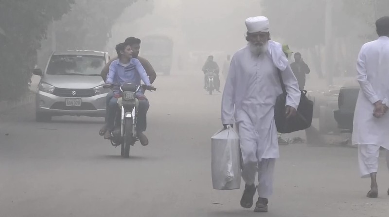 Para siswa terlihat siluetnya saat menyeberangi jembatan penyeberangan di tengah kabut asap dan polusi udara di pagi hari, di Karachi, Pakistan, 29 Oktober 2025. (REUTERS/Akhtar Soomro)