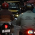 Pengendara motor melintasi jalanan padat di tengah kemacetan kota