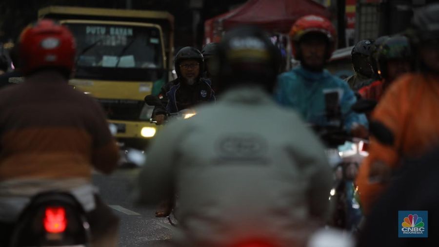 Pengendara motor melintasi jalanan padat di tengah kemacetan kota