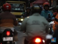 Pengendara motor melintasi jalanan padat di tengah kemacetan kota