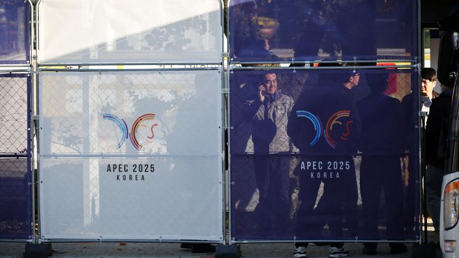 APEC-SUMMIT/ People stand behind fences bearing the logo of 2025 Asia-Pacific Economic Cooperation leaders' summit, at the venue for the summit in Gyeongju, South Korea, October 28, 2025.   REUTERS/Kim Hong-Ji