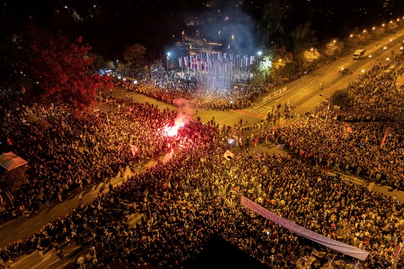 Pemandangan drone menunjukkan para demonstran menyalakan suar saat para pelajar yang ikut serta dalam pawai protes tiba di Novi Sad untuk memperingati ulang tahun pertama runtuhnya kanopi stasiun kereta api yang fatal pada November 2024, yang menewaskan 16 orang dan memicu tuduhan korupsi dan kelalaian di seluruh negeri, di Novi Sad, Serbia, 31 Oktober 2025. Pemandangan drone menunjukkan para demonstran menyalakan suar saat para pelajar yang ikut serta dalam pawai protes tiba di Novi Sad untuk memperingati ulang tahun pertama runtuhnya kanopi stasiun kereta api yang fatal pada November 2024, yang menewaskan 16 orang dan memicu tuduhan korupsi dan kelalaian di seluruh negeri, di Novi Sad, Serbia, 31 Oktober 2025. (REUTERS/Djordje Kojadinovic)