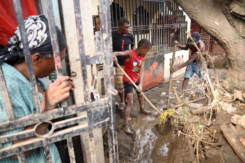 Warga membersihkan lumpur dan puing-puing di luar rumah setelah hujan lebat yang dibawa oleh Badai Melissa menyebabkan banjir mematikan, di Petit Goave, Haiti, 31 Oktober 2025. (REUTERS/Egeder Pq Fildor)