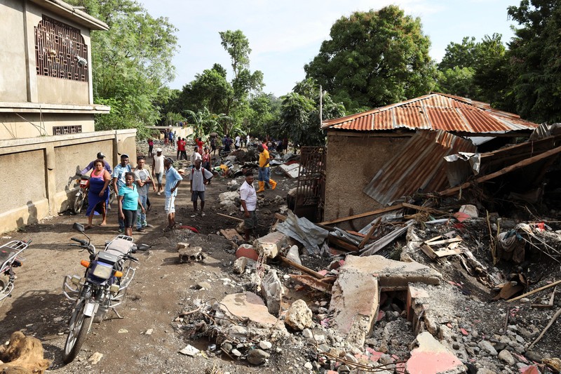 Warga membersihkan lumpur dan puing-puing di luar rumah setelah hujan lebat yang dibawa oleh Badai Melissa menyebabkan banjir mematikan, di Petit Goave, Haiti, 31 Oktober 2025. (REUTERS/Egeder Pq Fildor)