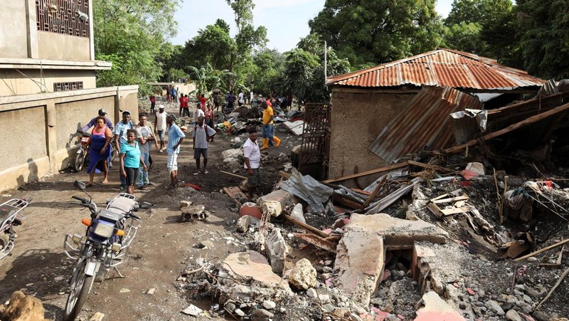 Warga membersihkan lumpur dan puing-puing di luar rumah setelah hujan lebat yang dibawa oleh Badai Melissa menyebabkan banjir mematikan, di Petit Goave, Haiti, 31 Oktober 2025. (REUTERS/Egeder Pq Fildor)