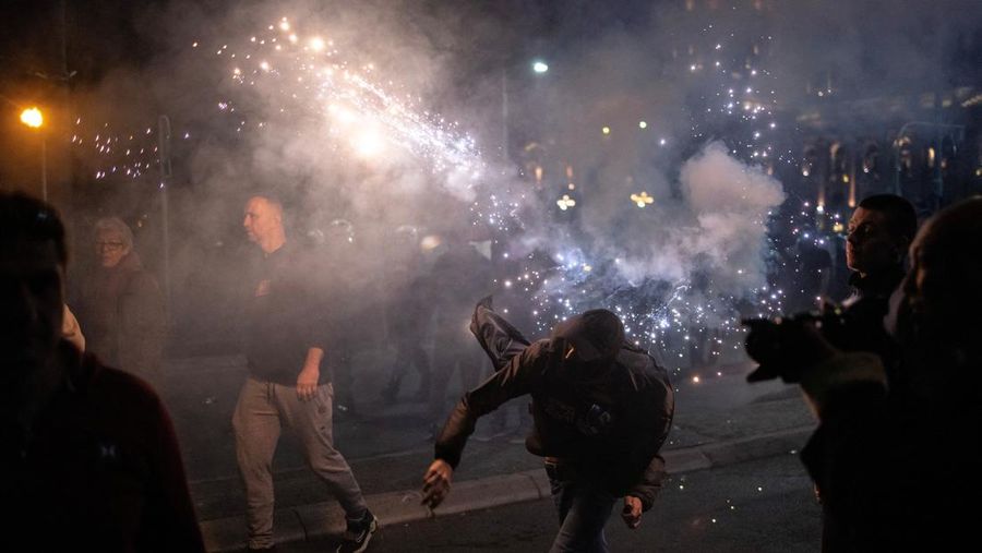 Seorang demonstran antipemerintah memberi isyarat di depan petugas penegak hukum dengan perlengkapan anti huru hara di dekat parlemen di Beograd, Serbia, 2 November 2025. (REUTERS/Marko Djurica)